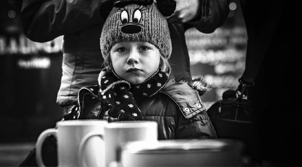 Дитина у в’язаній шапці за столом із чашками